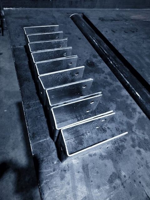 A row of formed steel brackets standing on the table
