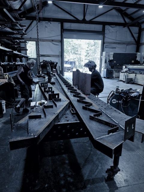 Two men work on long stair stringers laid across the fixture table