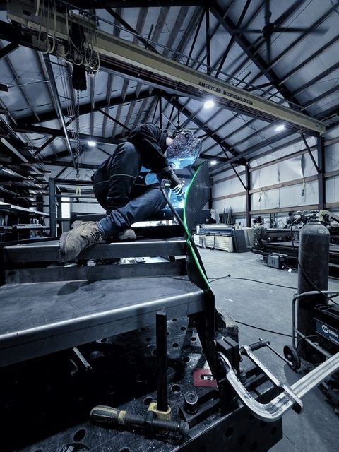 A welder in a hood sits up on the stair, welding